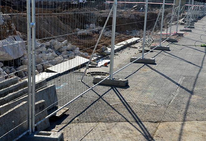 a row of temporary fence panels at a job site, providing safety and security